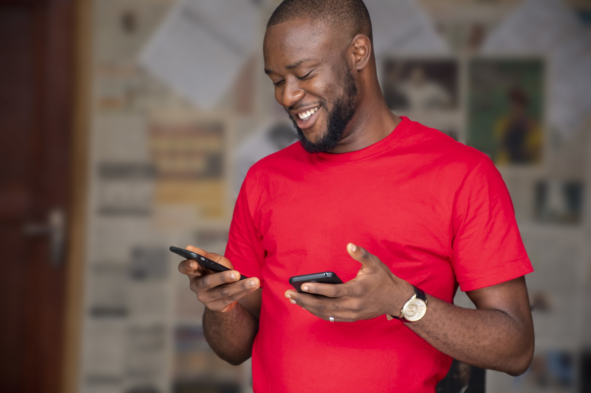 shallow-focus-young-african-male-using-two-phones-room